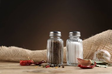 Ahşap masa üzerinde baharatlı tuzluk ve biber karıştırıcılar kahverengi eğimli arka plan, yakın çekim