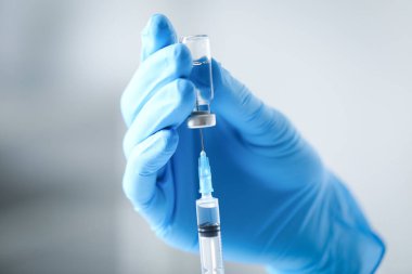 Hemşire şırıngayla aşıyı şişeden alıyor, yakın plan.