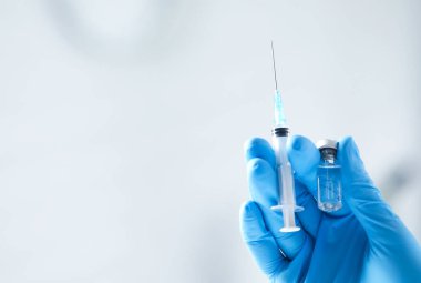 Hafif arka planda aşı ve şırınga şişesi olan hemşire, yakın plan. Metin için boşluk