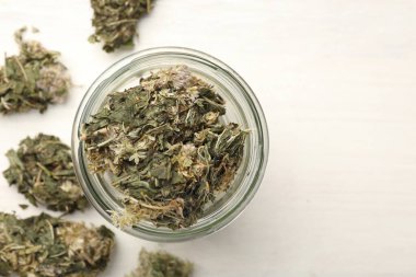 Kavanozda kurutulmuş şifalı bitkiler, beyaz ahşap masada, düz yerde. Metin için boşluk