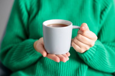 Kapalı mekanda çay içen bir kadın, yakın plan.