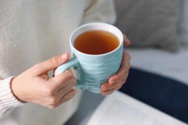 Kanepede sıcak çay içen bir kadın, yakın plan. Metin için boşluk