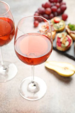 Bardakta şarap, lezzetli bruschette ve gri masada taze meyveler, yakın plan.