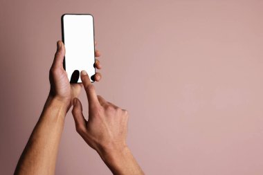 Dusty Rose arka planında boş ekranlı akıllı telefon tutan adam, yakın plan. Tasarım için model