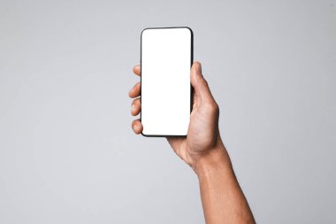 Açık gri arka planda boş ekranlı akıllı telefon tutan adam, yakın plan. Tasarım için model