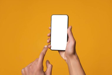 Turuncu arka planda boş ekranlı akıllı telefon tutan adam, yakın plan. Tasarım için model