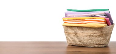 Çamaşır sepetinin üzerinde beyaz arka planda giysiler var.