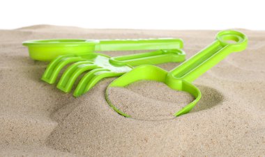 Çocuklar için plaj oyuncakları ve beyaz pankartta izole edilmiş kum. Plastik elek, tırmık ve kürek.