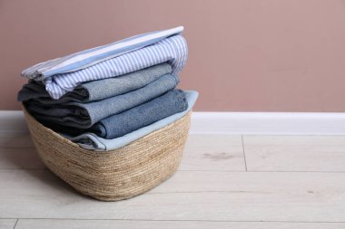 Çamaşır sepetinin içinde bej duvarın yanında giysiler var. Metin için boşluk