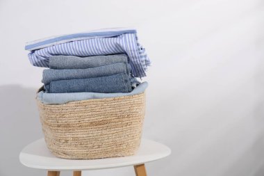 Çamaşır sepetinin içinde beyaz duvarın yanındaki masada giysiler var. Metin için boşluk