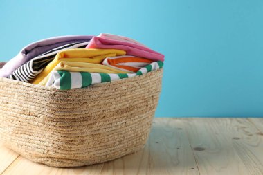 Açık mavi duvarın yanındaki ahşap masada giysileri olan çamaşır sepeti, yakın plan. Metin için boşluk