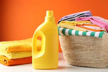 Çamaşır sepetinin içinde giysiler, havlular ve bir şişe deterjan var.