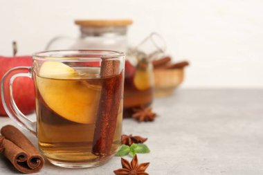 Cam fincanda aromatik meyve çayı, çaydanlık, elma, nane ve baharatlar gri masada, yakın plan. Metin için boşluk