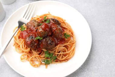 Açık gri masada servis edilen köfteli lezzetli makarna, yakın plan.