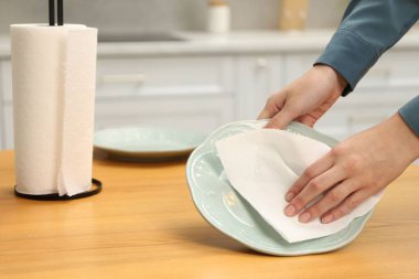 Mutfaktaki tahta masada kağıt havluyla silen kadın, yakın plan.