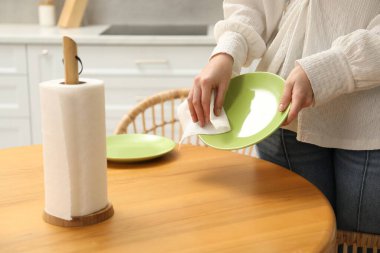 Mutfaktaki tahta masada kağıt havluyla silen kadın, yakın plan.