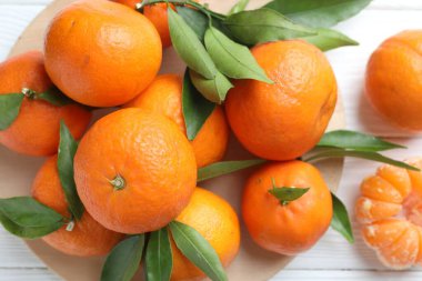 Taze mandalina ve yeşil yapraklar beyaz ahşap masada, düz yatıyordu.