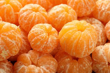 Arka plan olarak birçok olgun soyulmuş mandalina, yakın plan