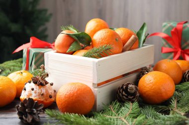 Olgun mandalinalar, baharatlar, köknar ağacı dalları ve koniler masada, yakın plan.