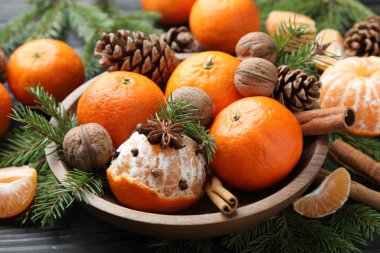 Olgun mandalinalar, baharatlar, cevizler, köknar ağacı dalları ve tahta masanın üzerindeki koniler, yakın plan.