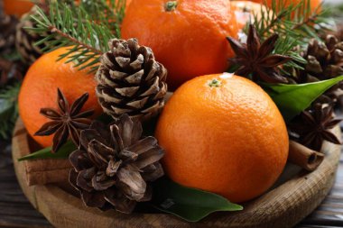 Olgun mandallar, baharatlar, köknar ağacı dalları ve tahta masanın üzerindeki koniler, yakın plan.