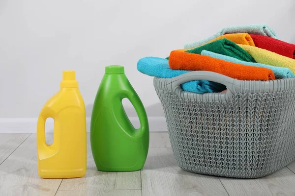Çamaşır sepetinin içinde havlular ve şişe deterjan var.