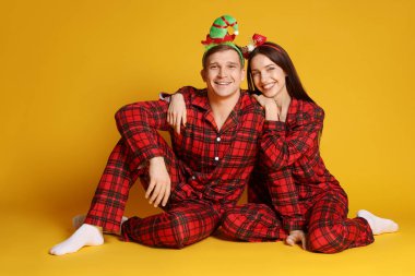 Turuncu arka planda komik bantlı ve pijamalı mutlu bir çift. Noel atmosferi