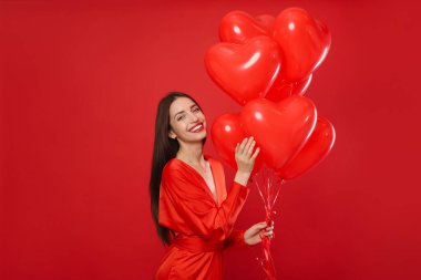 Sevgililer Günü. Kırmızı arka planda kalp şeklinde balonları olan güzel bir kadın. Metin için boşluk