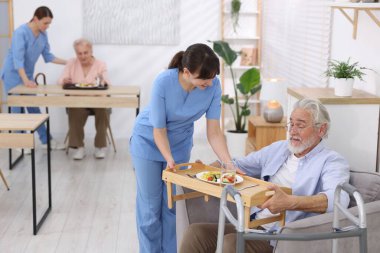 Huzurevinde yaşlılara yemek servisi yapan bakım işçisi.