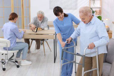 Huzurevinde yaşlı kadına Walker 'la yardım eden bakım işçisi.