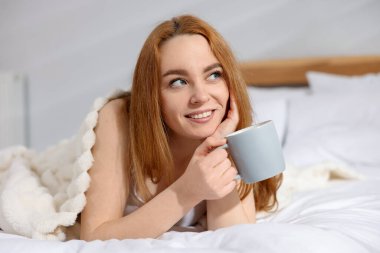 Evde yatağında bir fincan kahveyle güzel bir kadın.