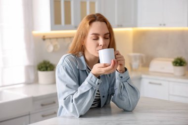 Mutfakta taze kahve içen bir kadın.