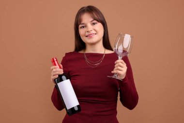 Soluk kahverengi arka planda kırmızı şarap ve cam şişesi olan profesyonel şarap garsonu.