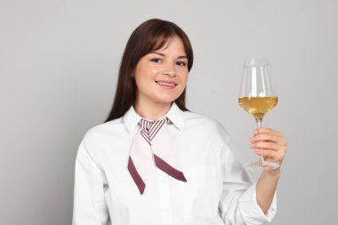 Açık gri arka planda beyaz şarap kadehi olan profesyonel şarap garsonu.