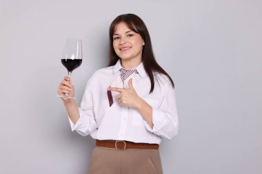 Açık gri arka planda kırmızı şarap kadehi olan profesyonel şarap garsonu.