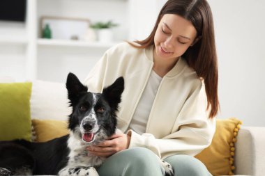 Evdeki kanepesinde Collie köpeği olan bir kadın.