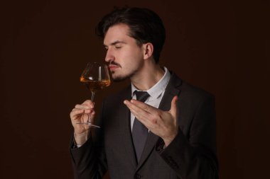 Profesyonel şarap garsonu kahverengi arka planda beyaz şarap tadıyor. Metin için boşluk