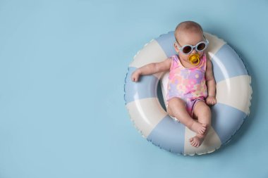 Güneş gözlüklü, emzik takan, açık mavi arka planda, şirin bir bebek. Metin için boşluk