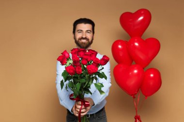 St. Valentine's Day. Man with bouquet and heart shaped balloons on beige background