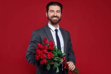 Sevgililer Günü. Kırmızı arka planda gül buketi olan yakışıklı adam.