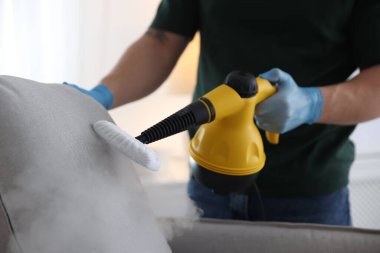Haşere kontrol işçisi temizlik yastığını içeride buhar temizleyicisiyle temizliyor, yakın plan.