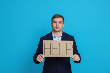 İşadamı tabelayı elinde tutuyor Açık mavi arka planda yardım