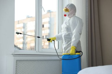 Koruyucu giysiler içinde böcek ilacı sıkan haşere kontrol görevlisi.