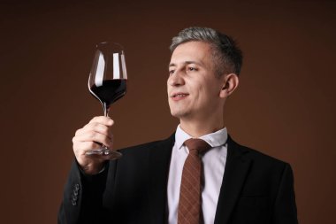 Kahverengi arka planda kırmızı şarap kadehi olan profesyonel şarap garsonu.