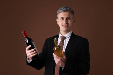 Kahverengi arka planda şarap şişeleri olan profesyonel şarap garsonu.