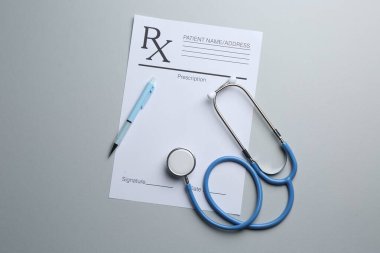 Boş alanlar, steteskop ve açık gri zemin üzerine kalem içeren tıbbi reçete formu, düz uzanma
