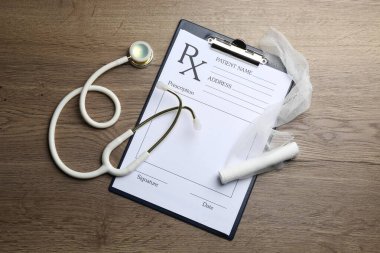 Tahta masada boş tarlalar, steteskop ve sargı bezi olan tıbbi reçete formu.