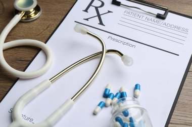 Boş tarlalar, steteskop ve ahşap masa üzerindeki haplarla dolu tıbbi reçete formu.