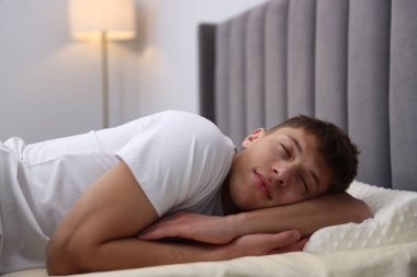 Genç adam evde ortopedik yastıkla uyuyor. Sağlıklı duruş