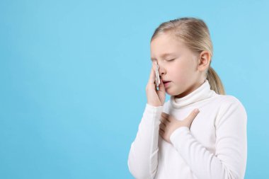 Açık mavi arka planda burnu akan küçük bir kız, mesaj için yer var. Soğuk Semptom